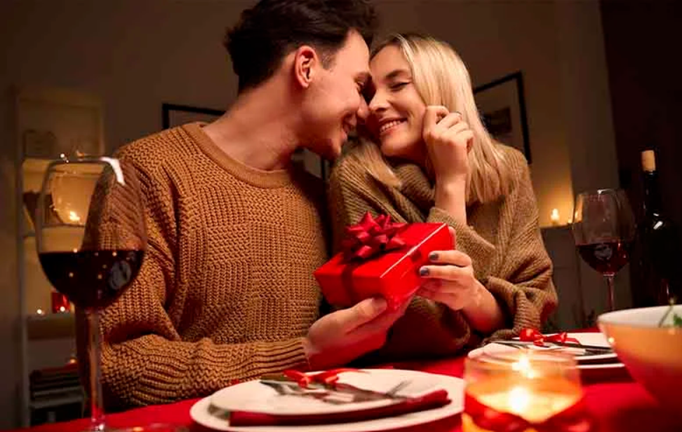 Dois namorados em um jantar romântico e o namorado dando um presente que escolheu para a namorada no dia dos namorados