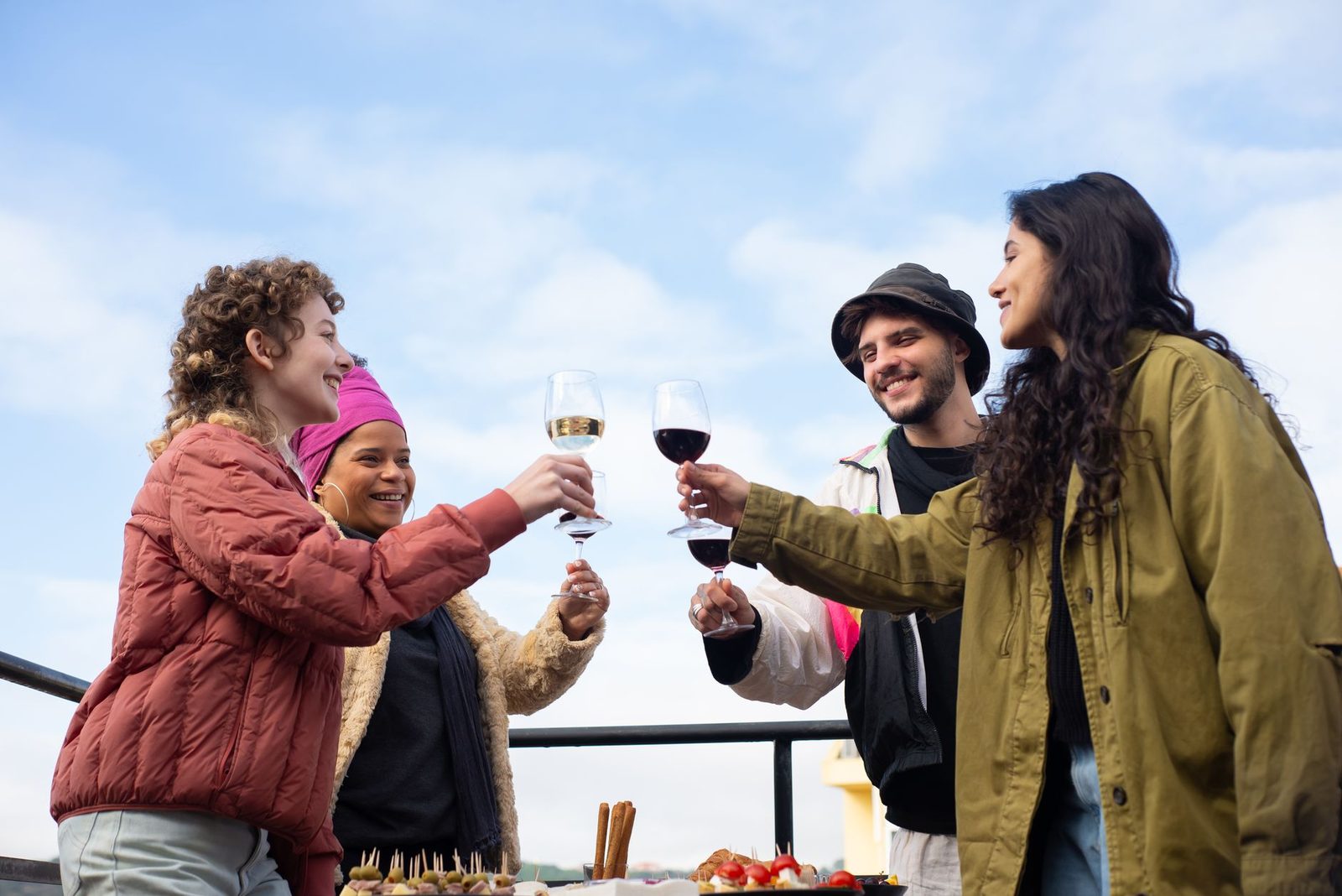 Um grupo de amigos celebrando com vinho ao ar livre em Portugal sob um céu azul claro