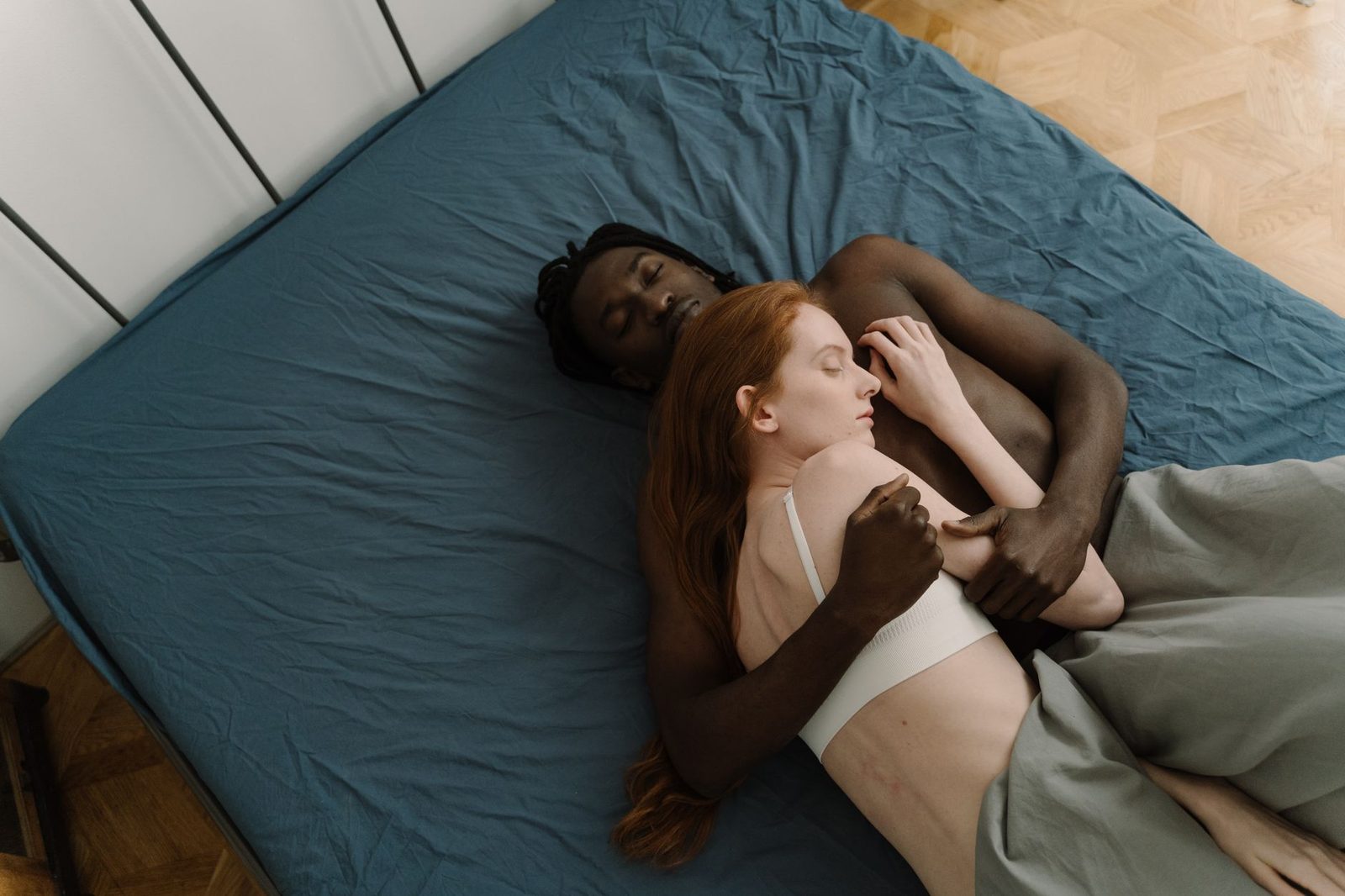 Um casal interracial compartilha um abraço íntimo na cama, simbolizando amor e união