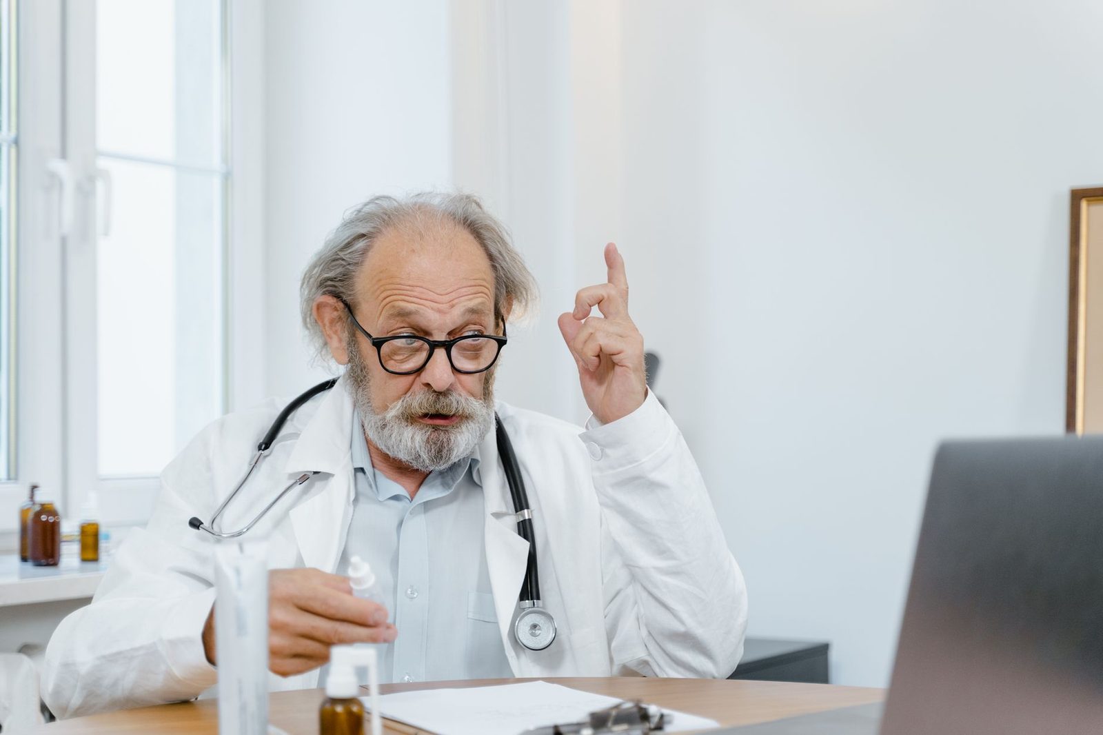 Médico sênior com jaleco branco realizando uma consulta online. Profissional de saúde usando tecnologia para cuidados médicos