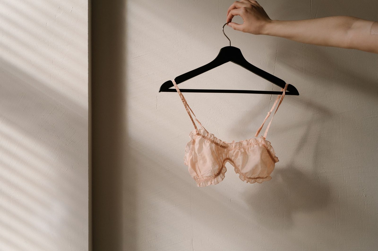 Um delicado sutiã rosa em um cabide, capturado em um ambiente interno minimalista com iluminação suave